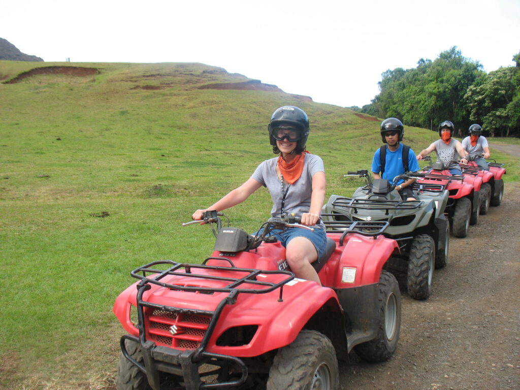 Four people riding ATVs with Godzilla’s giant footprints at Kualoa Ranch as backdrop