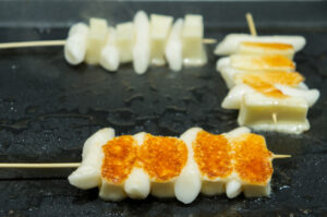 Skewers of baked and grilled mozarella cheese in between rice cakes.