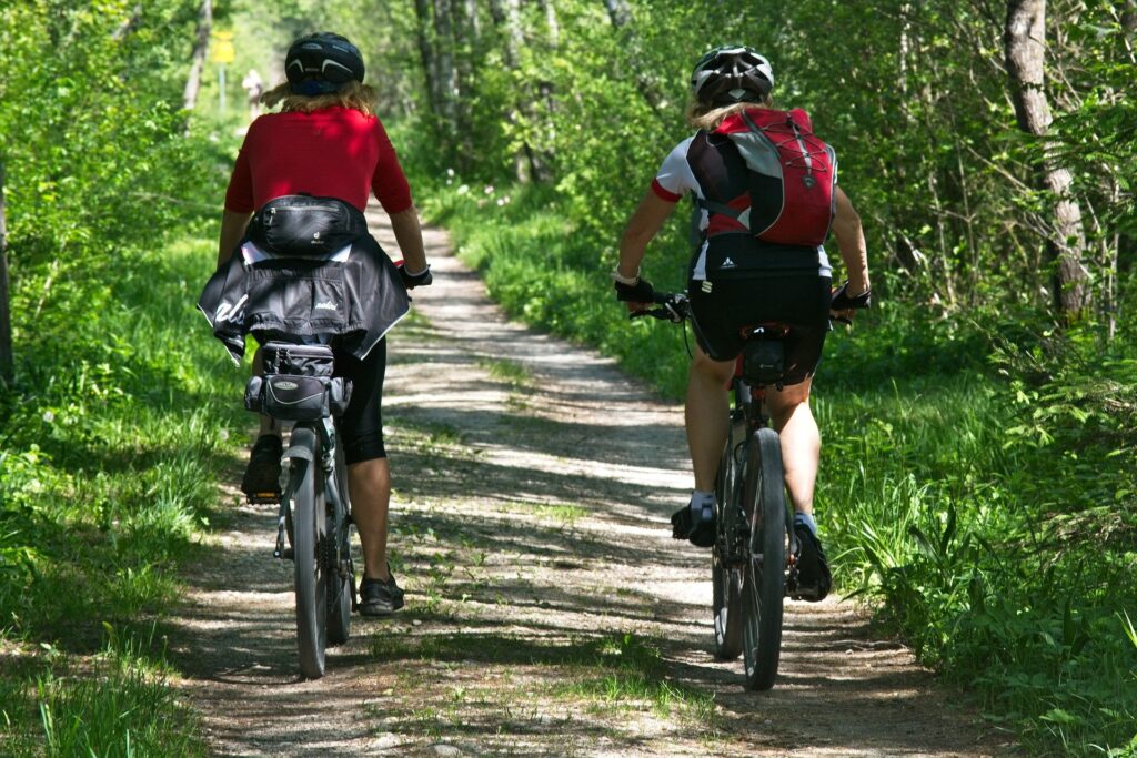 Two people riding a bike in the woods.