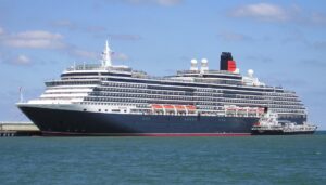 A small boat beside a moored cruise ship.