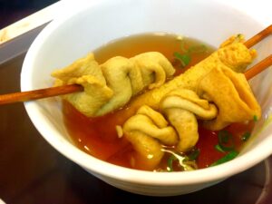 Fishcake skewers in a bowl of hot soup.