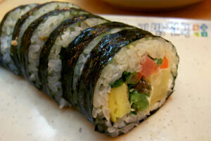 A roll of kimbap with vegetables and egg fillings.