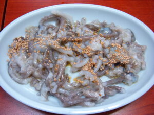 A plat of small live octopus topped with sesame seeds and chilli oil.