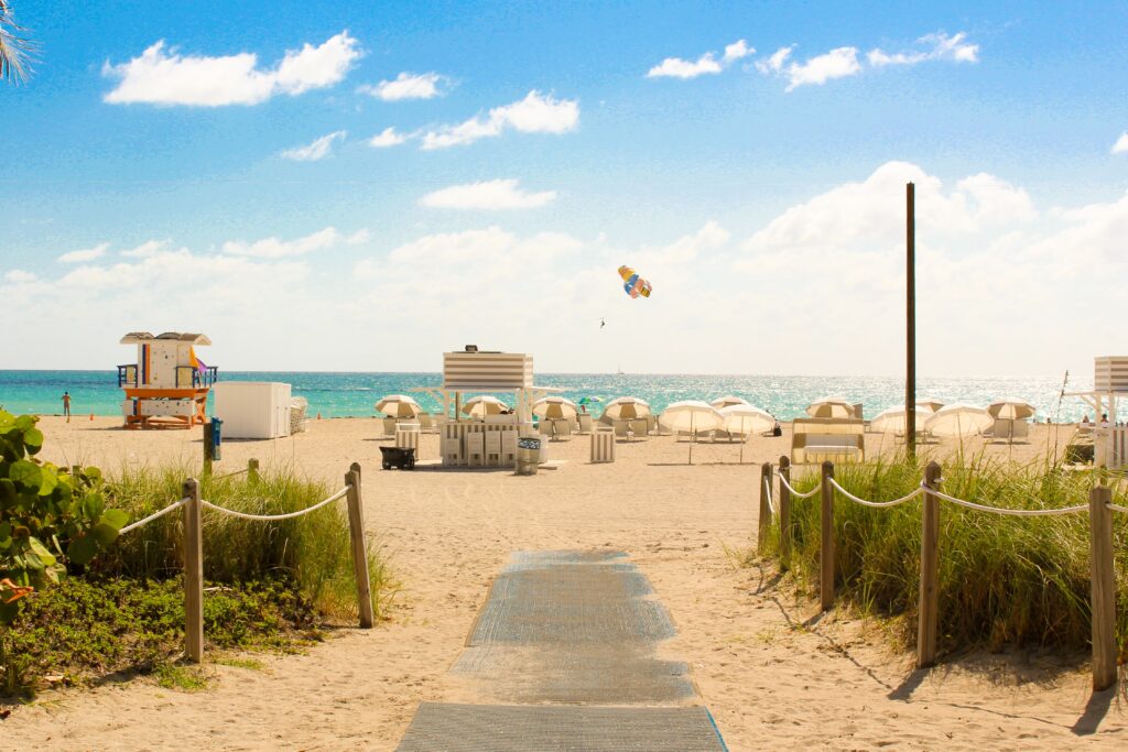 White umbrellas braced on white-sand beach