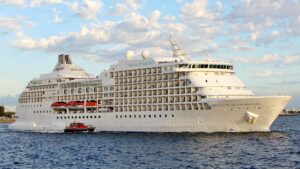 A white cruise ship near the coast with a label that says Seven Seas Navigation.