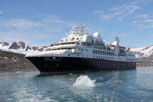 A ship docked near snow capped mountains.