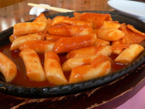 Spicy Rice Cakes (Tteokbokki), a famous Korean street food, in a plate of spicy red sauce.