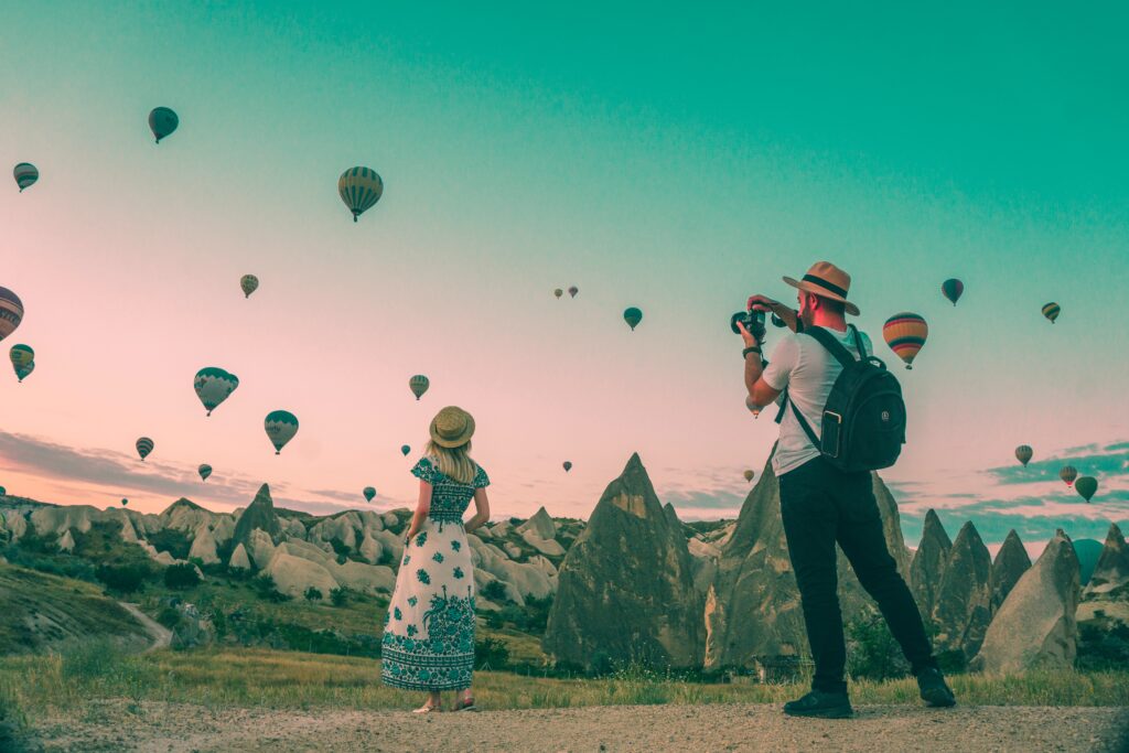 Boy taking a photo of a girl with balloons on the background