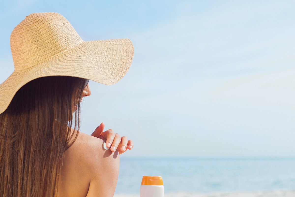 Woman applying sunscreen by the beach