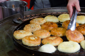 Hotteok or sweet pancakes getting cooked in a pan grill.