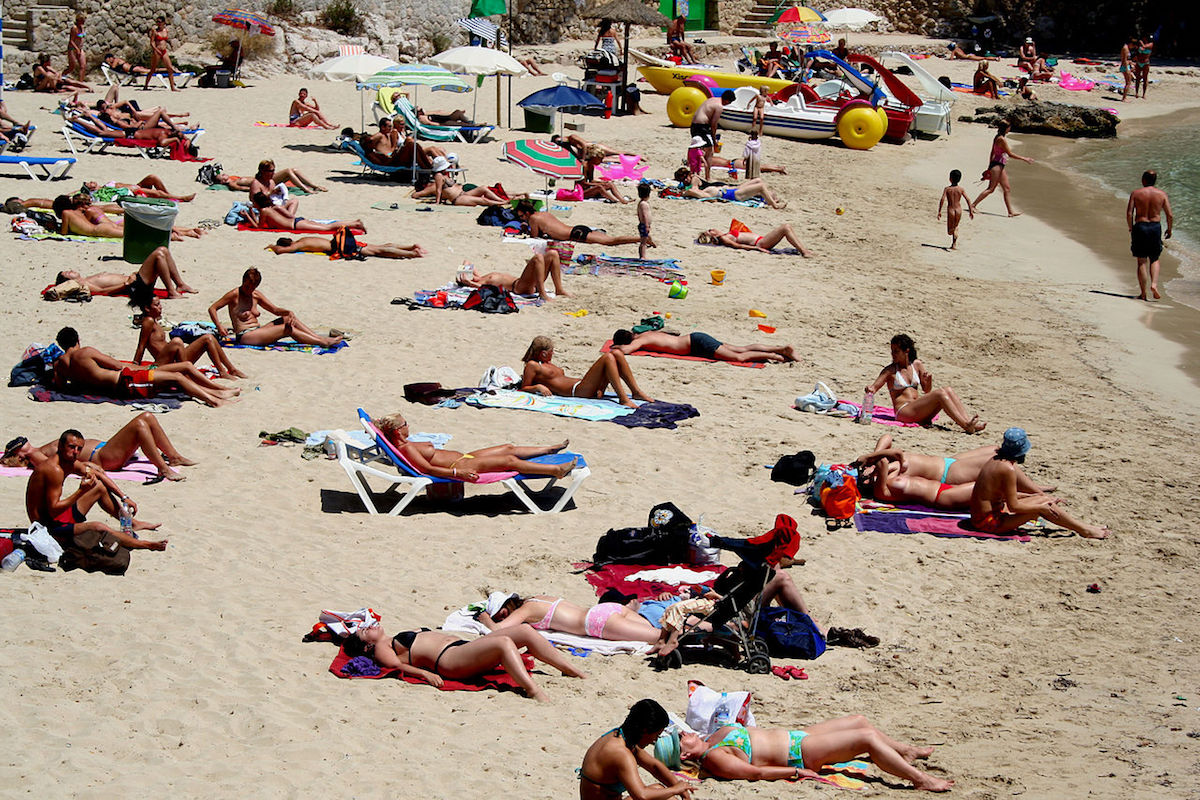 Topless women and men sunbathing on the beach