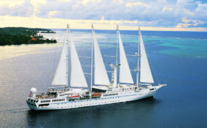 A white ship with 5 white triangular sails in the open sea.