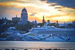 A docked ship labeled as Norwegian Dawn with towers and domes behind.