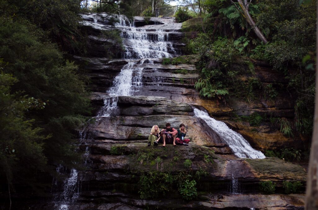 Three people sitting on a waterfall ledge