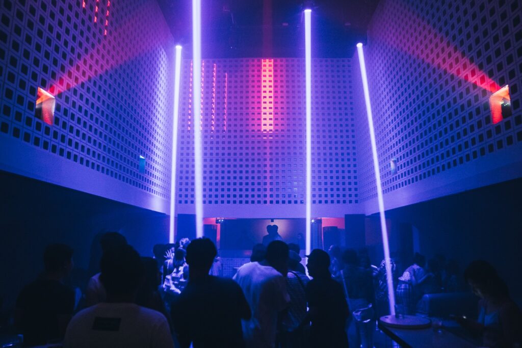 People inside a dark room with beam of lights.