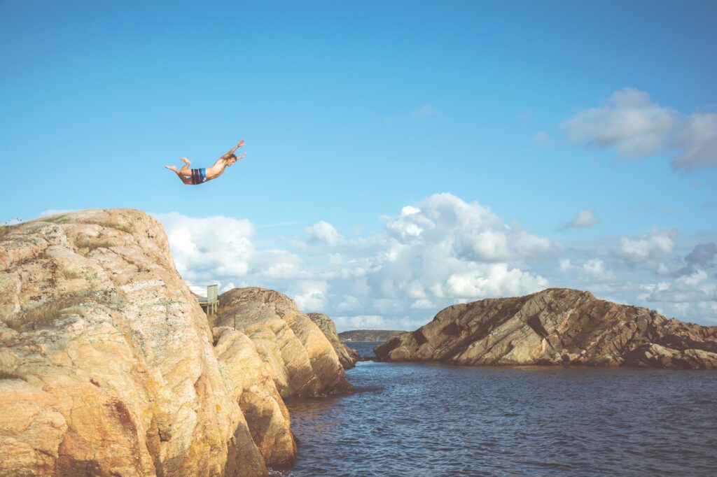 A man jumping from a cliff into the water.