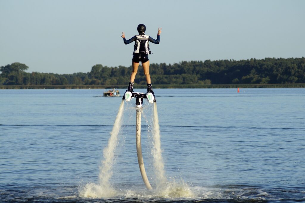 A girl riding a flyboard poses in peace sign.