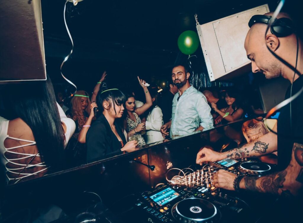 A DJ operating an audio mixer in front of a dancing crowd.