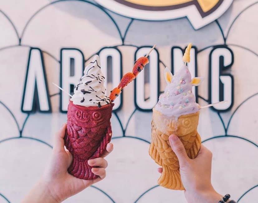 Two hands holding fish-shaped ice cream cones.