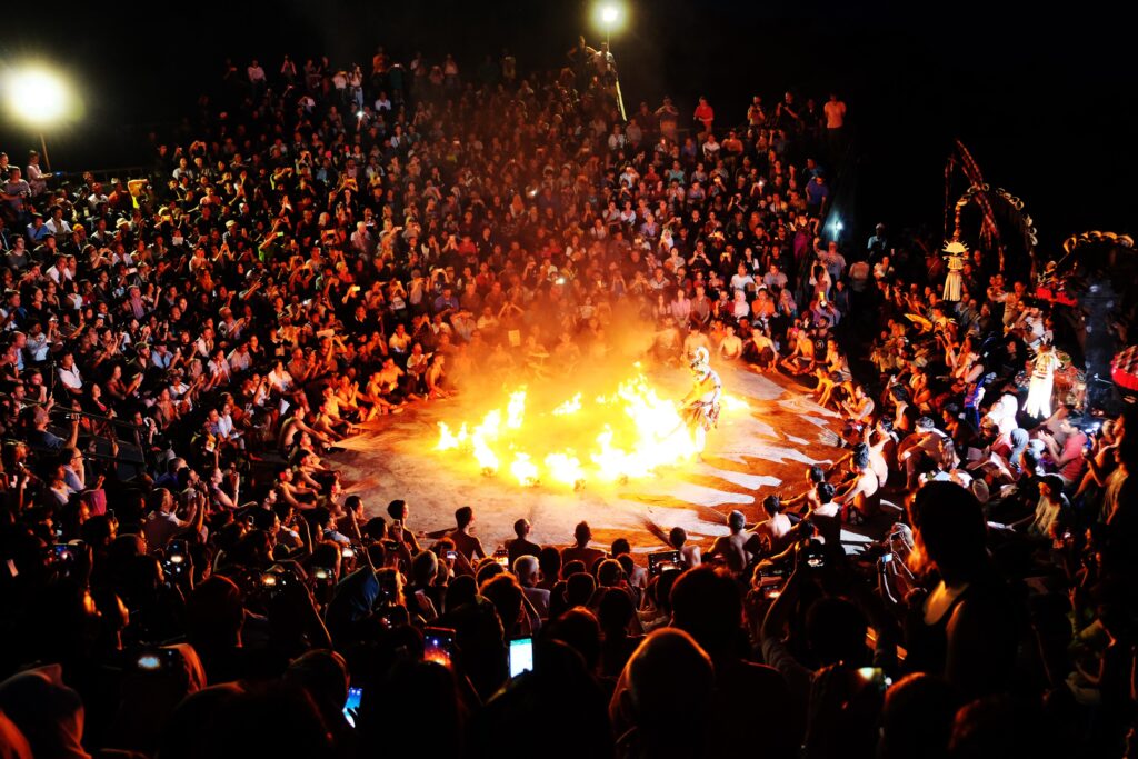 A crowd watching a fire dance performance at night.