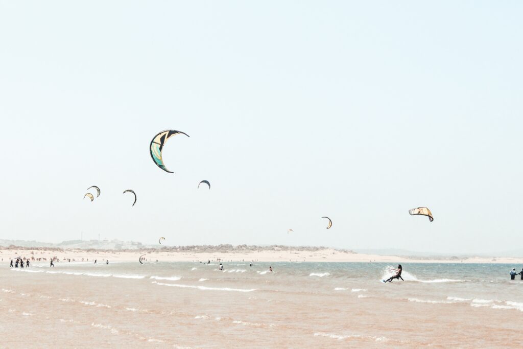 A group of people doing kite surfing near the coast.