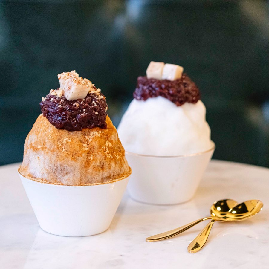 Two bowls of Korean Bingsu with 2 golden spoons on the side.