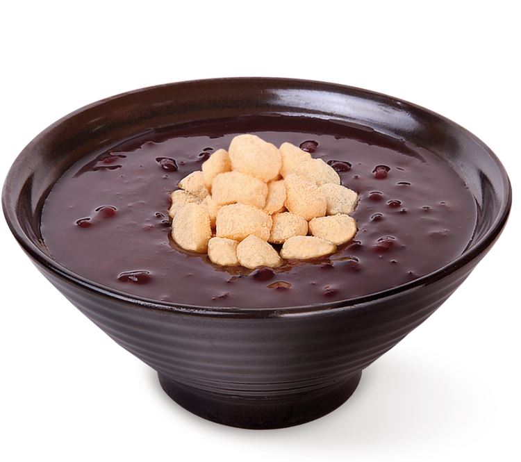 A bowl of red bean soup with rice cakes on top.