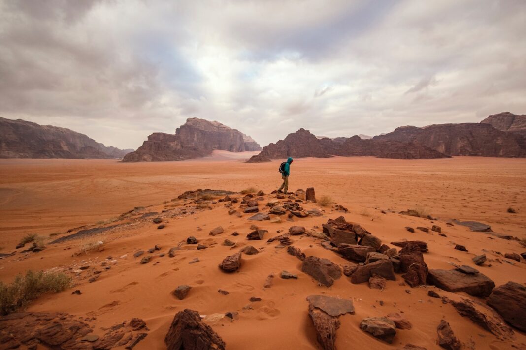 A guy traversing through the red sand desert in Jordan