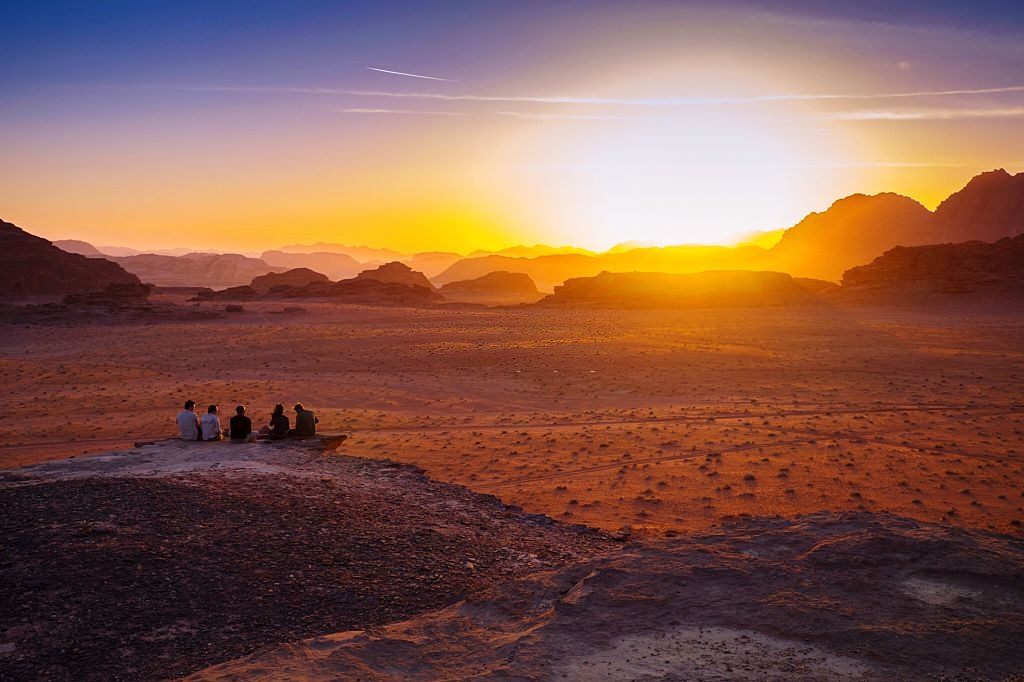 Friends enjoying sunset on a cliff in Jordan