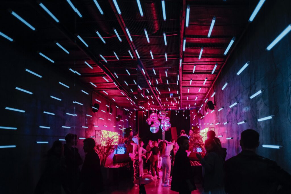 People inside a dark room with blue lights and disco balls.