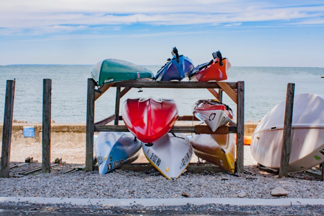 Assorted-color kayak piled on a rack near the sea.
