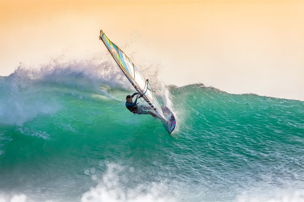 A guy doing wind surfing riding big waves.