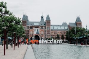 A park with a sign that says "I amsterdam" in front of a gabled building.