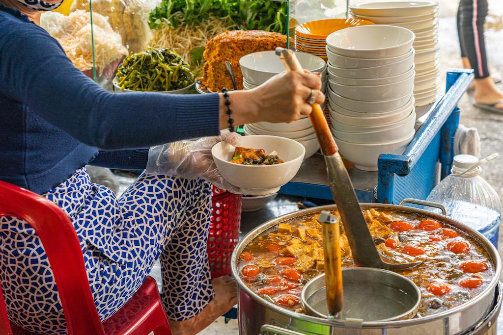 A street food vendor cooking crab paste and snail noodle soup at the street side of Hanoi