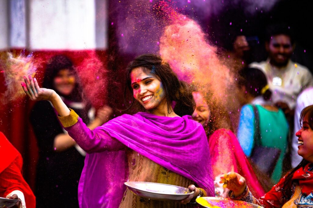 A woman throws colored powder in air during a Festival of Colors in India.