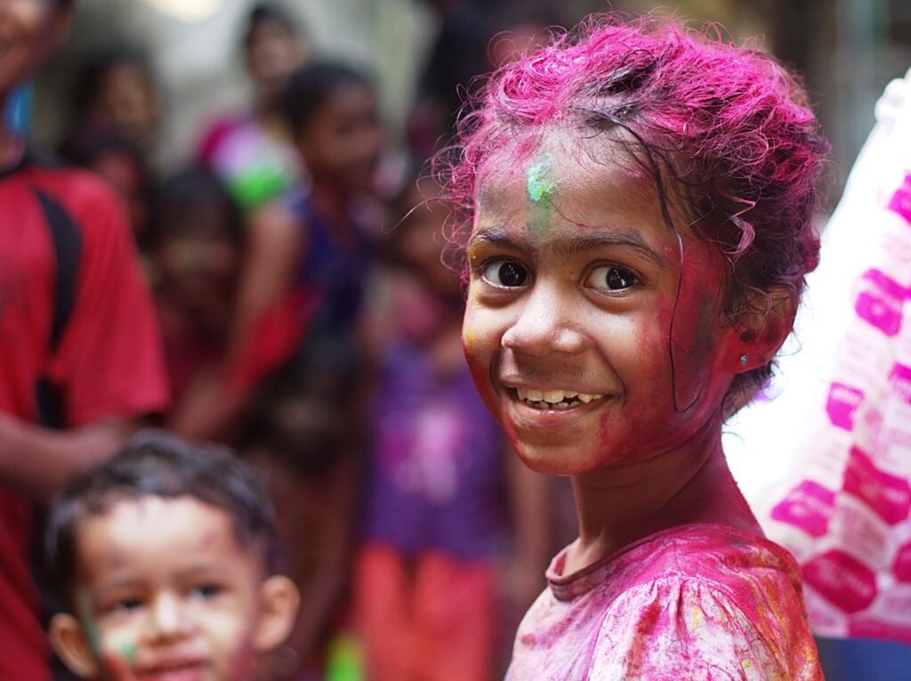 A smiling little girl covered with colored powder.