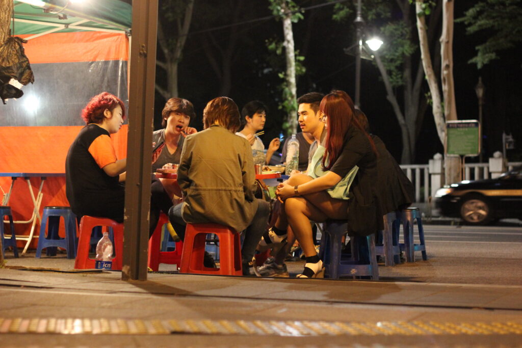 A group of people sitting outside a Pojangmacha, tent bars in Korea.