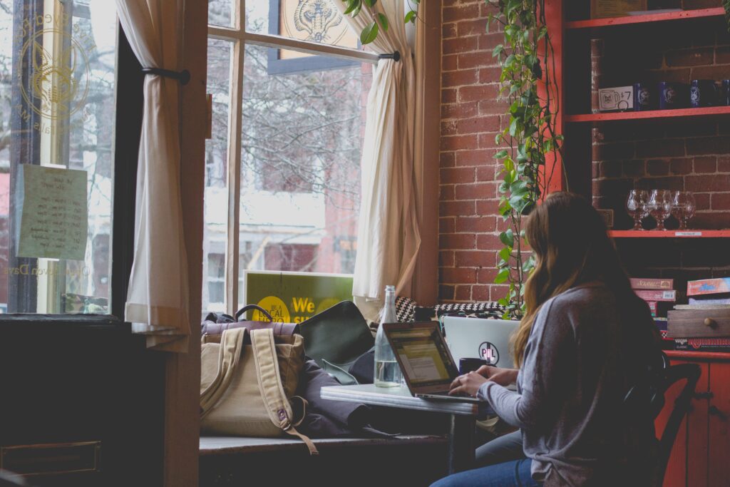 A girl using a laptop near the window.