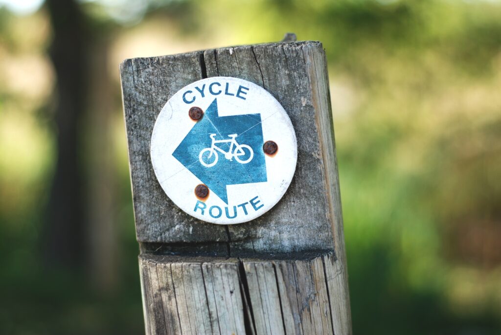 A sign in a wooden post that says cycle route.